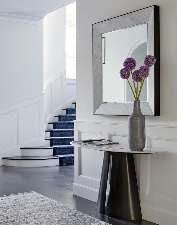 Adam Hunter designed framed mirror in entryway with purple flowers and runner.