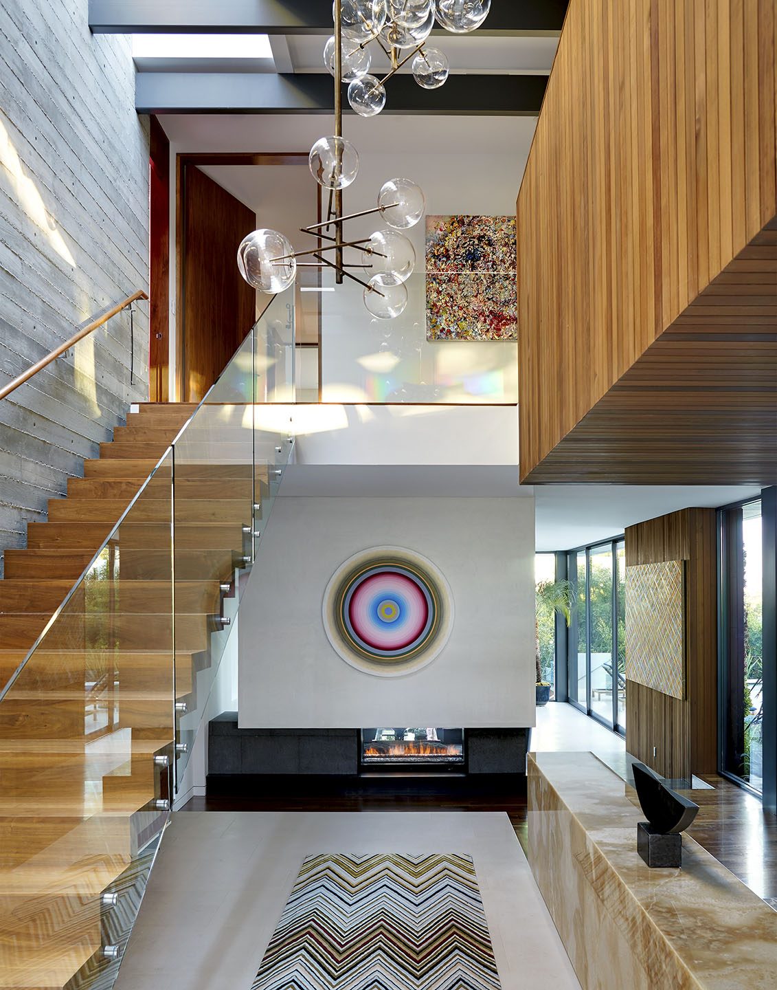 Adam Hunter designed foyer with a light fixture, rug and art at the end of the long hall.