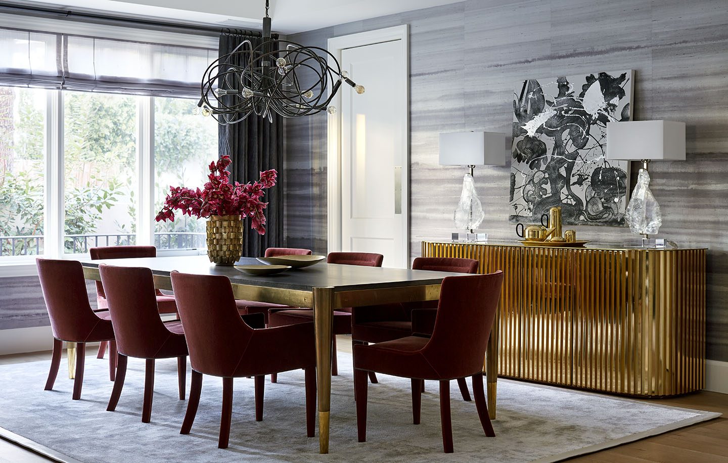 Adam Hunter designed dining room with a brass dining table and ruby red chairs.