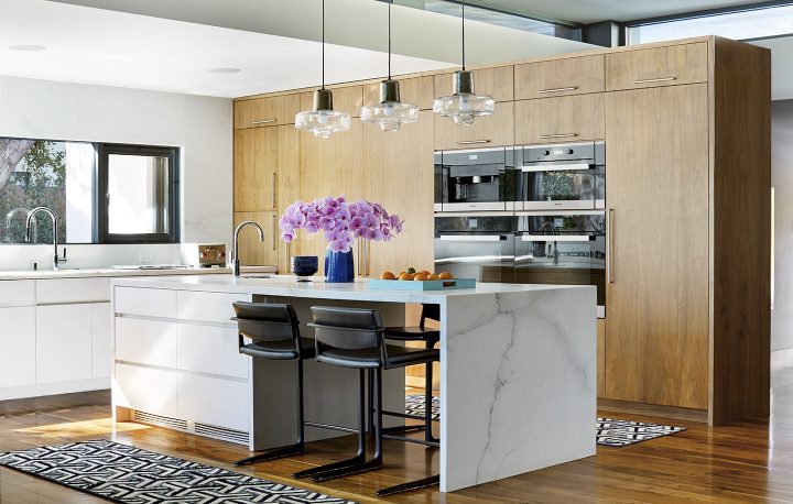 Adam Hunter designed kitchen with three light pendants and purple flowers.