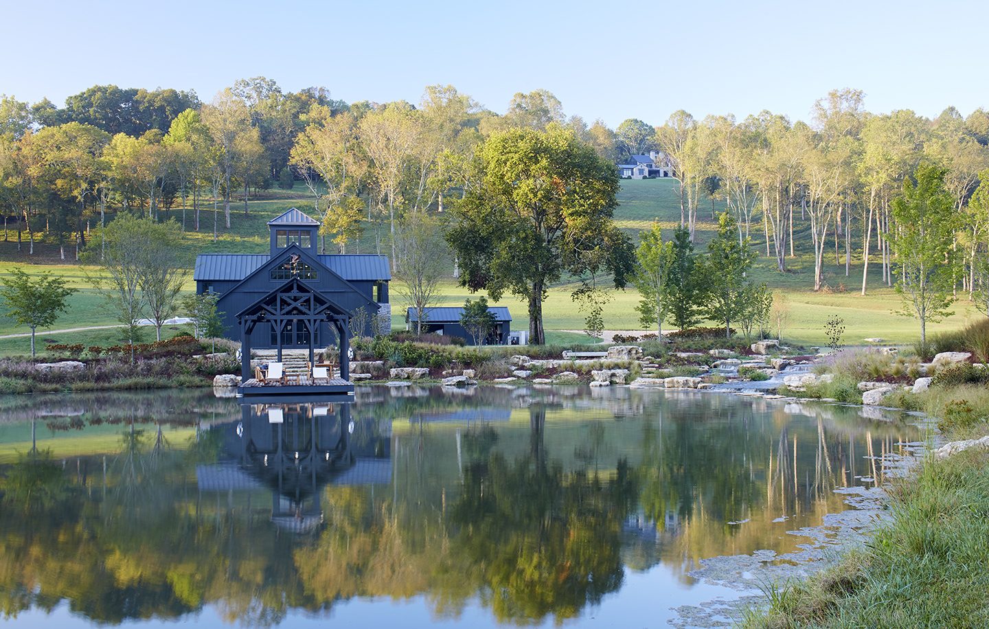 Adam hunter designed a property with multiple structures and a man made pond.